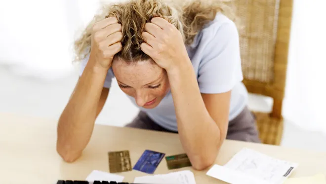 a woman in a desk in stress holding her head with her hands depicting a loss due to data breach or digital scam